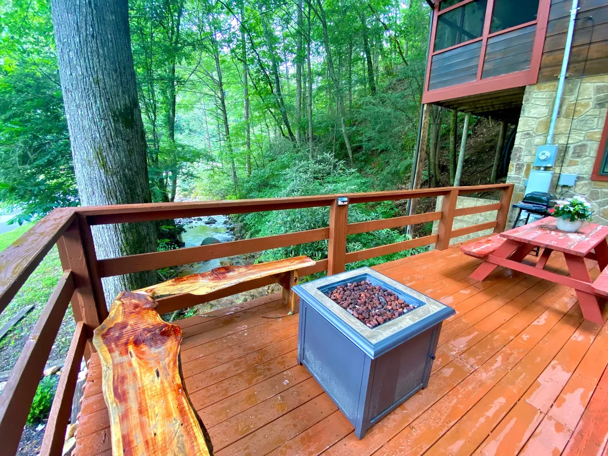 This exterior image features a cozy fire pit surrounded by wooden benches, all nestled within lush greenery. The tranquil setting is perfect for evening gatherings, stargazing, or simply unwinding with friends in the quiet embrace of nature.