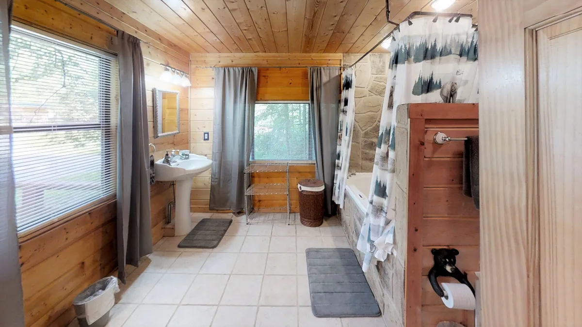 A tranquil bathroom with wooden paneling, a deep soaking bathtub, a spacious sink, and a window offering serene views. The space is bright, serene, and designed for relaxation.